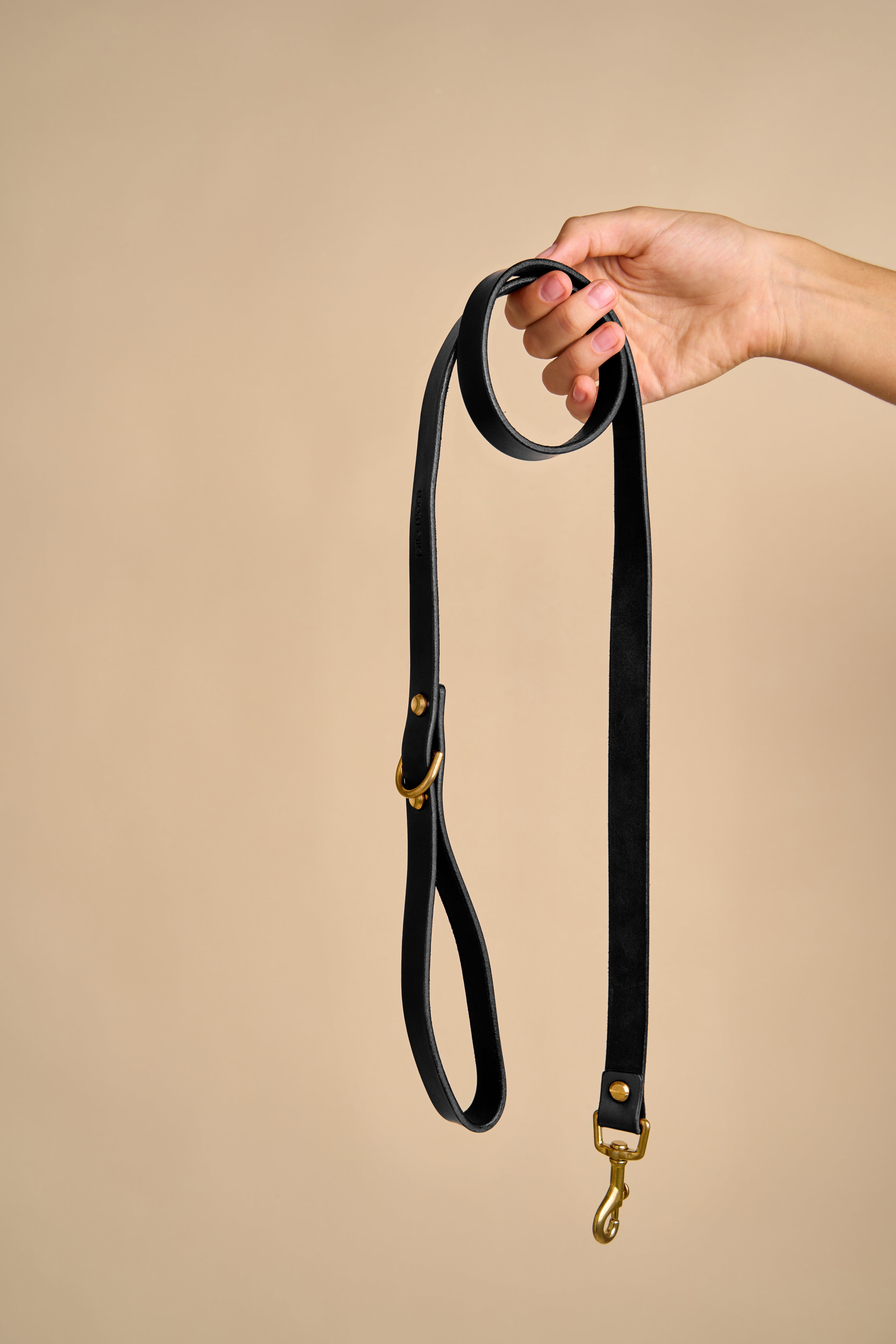 Full view of Classic Black Leather Dog Leash held in hand, made from premium Italian leather with brass hardware for strength