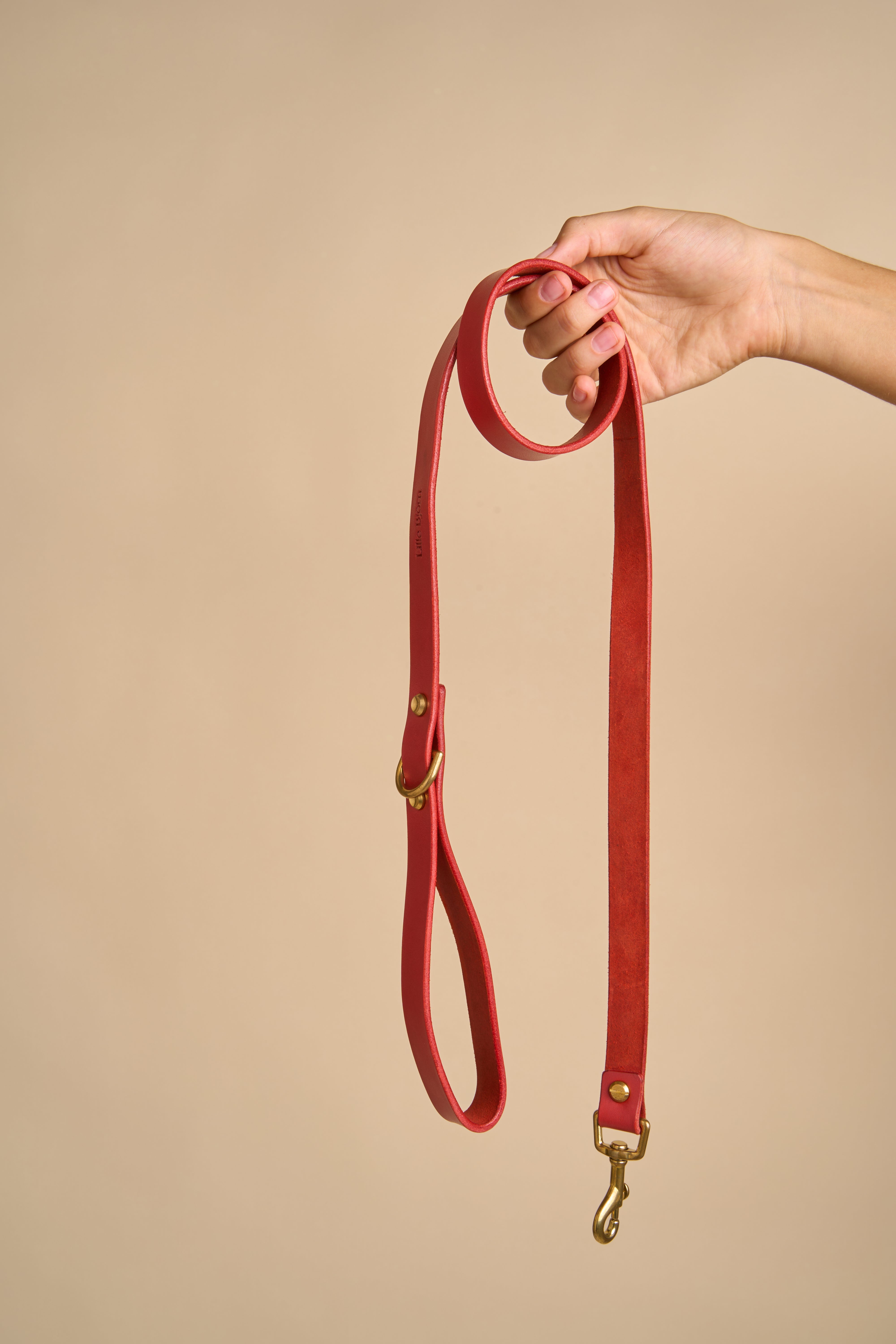 Full view of Classic Red Leather Dog Leash held in hand, made from premium Italian leather with strong brass hardware