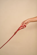 Classic Red Leather Dog Leash held in hand, demonstrating flexible handling, made from premium Italian leather with brass hardware