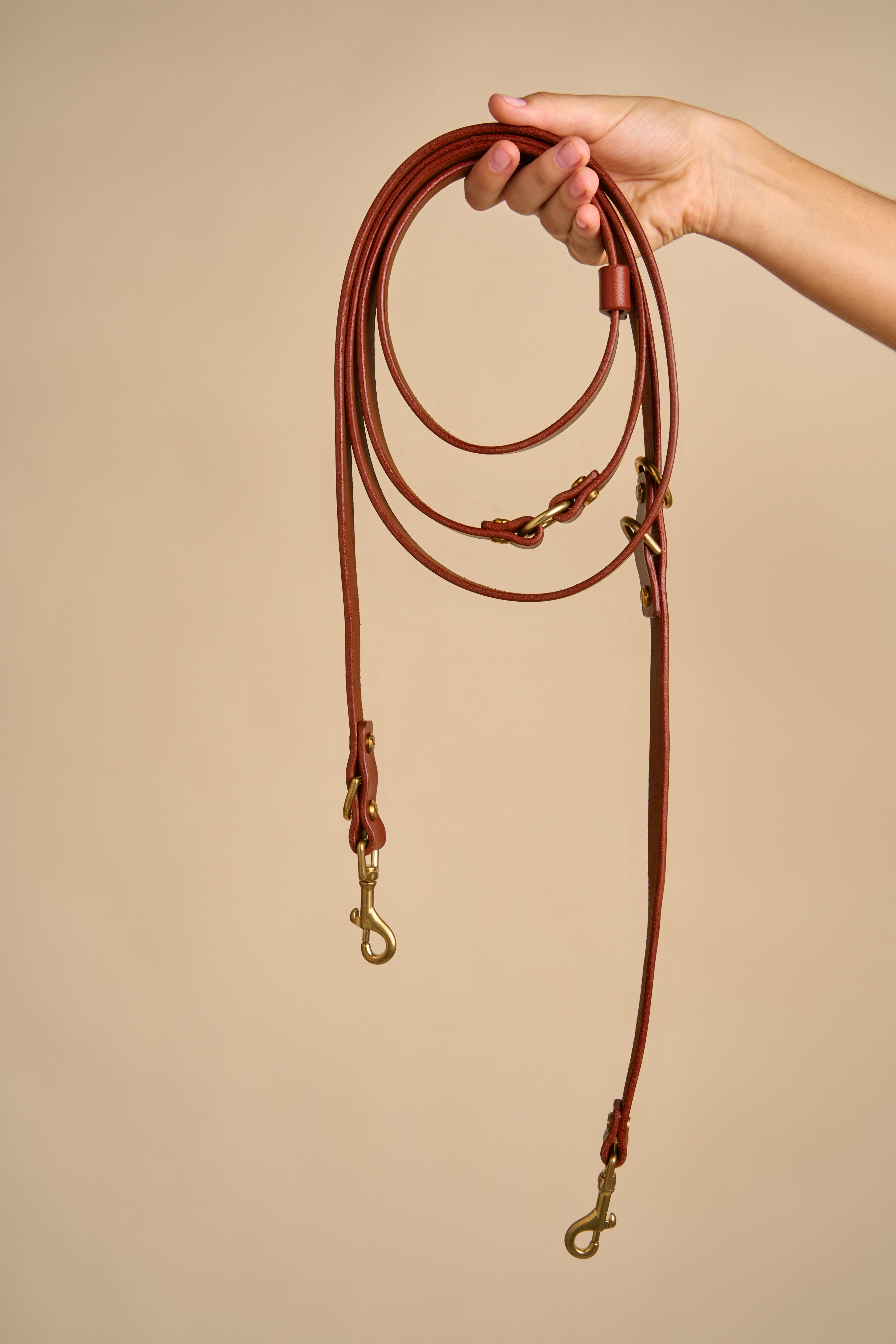 Full view of Omni Cognac Leather Dog Leash held in hand, featuring Italian craftsmanship and durable brass hardware