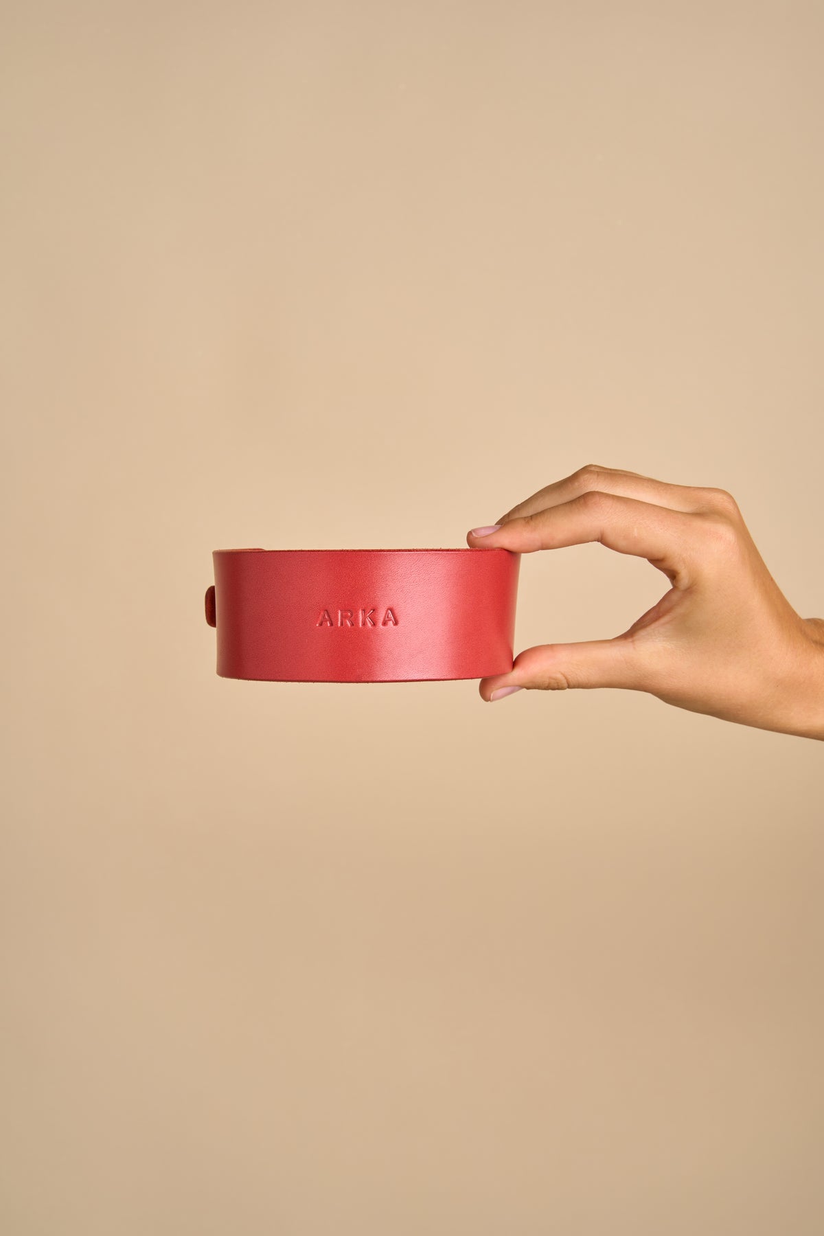 Close-up of personalized name embossing on Vero Wide Red Leather Dog Collar, held in hand, made from premium leather for customization